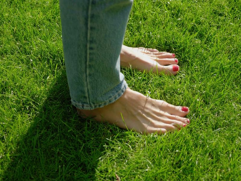 devojka sa nalakiranim noktima na nogama šeta bosa po travi